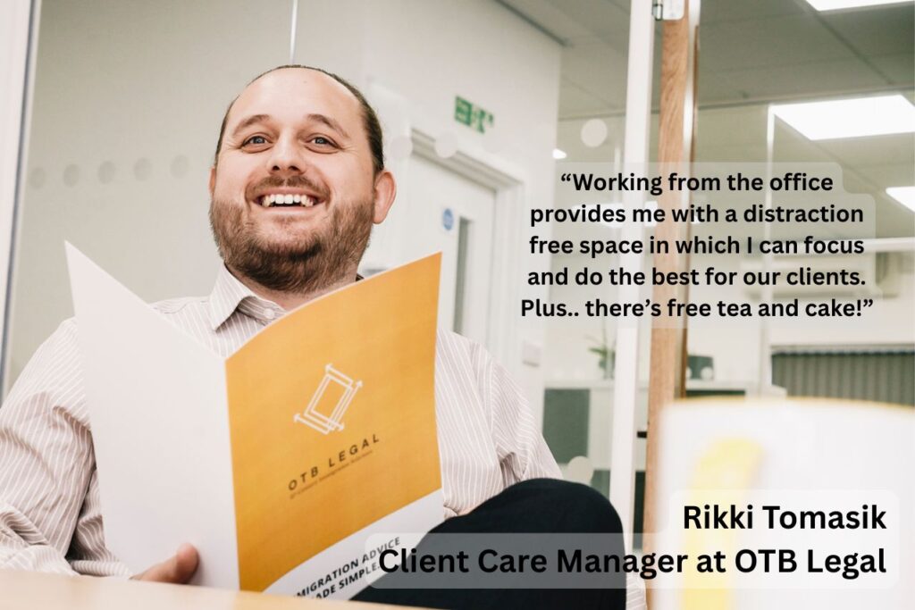 Man with a brochure smiling at his desk talking about working full time in the office
